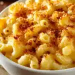 Close-up of creamy Classic Mac and Cheese in a white ceramic bowl with golden brown crispy breadcrumb topping and smooth cheddar cheese sauce on elbow macaroni