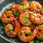 Close-up of air fryer shrimp teriyaki with a glossy sauce and garnished with sesame seeds.