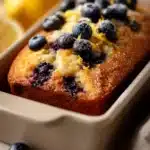 Close-up of a blueberry lemon muffin loaf with a golden crust and visible blueberries.