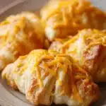 Close-up of cheesy chicken crescent rolls with golden brown crust and melted cheese.