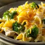 Close-up of chicken broccoli casserole with noodles, topped with cheese and herbs.