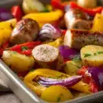 Close-up of a chicken sausage sheet pan meal with vegetables on a clean background