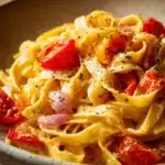 Close-up of creamy one pot pasta tagliatelle with herbs on a white plate.