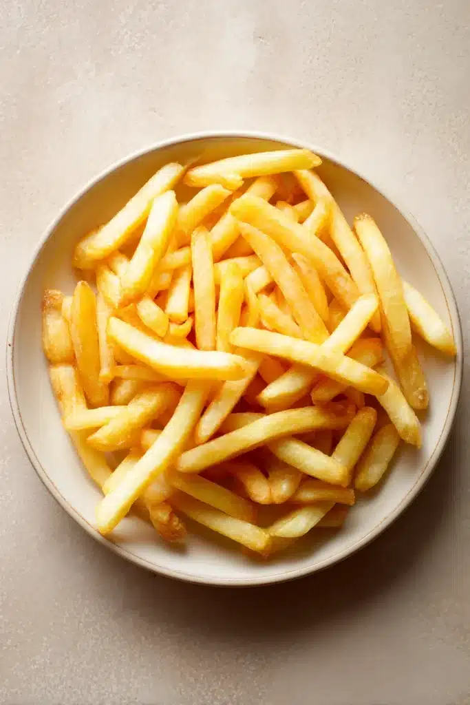 Close-up of crispy golden air fryer frozen french fries on a white plate.