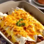 Close-up of breakfast enchiladas with melted cheese and fresh herbs.