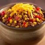 Close-up of a savory ground beef skillet dinner with vegetables and herbs in a warm, inviting setting.