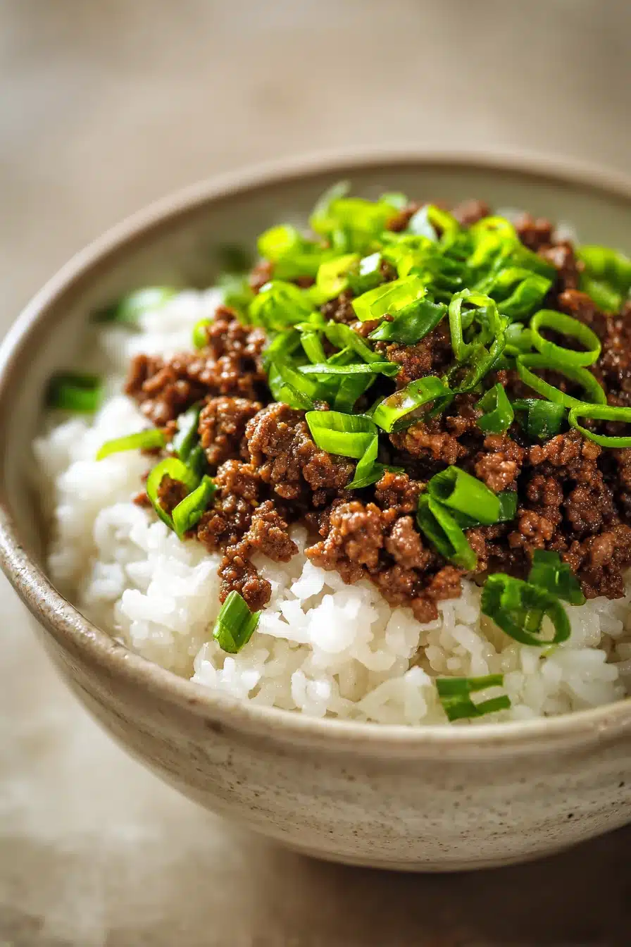 Close-up of a Korean ground beef bowl with rice and vegetables, garnished with sesame seeds.