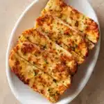 Close-up of garlic bread made with pizza dough, showcasing golden crust and herbs.