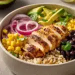 Close-up of a high protein chicken enchilada bowl with vibrant toppings and creamy sauce
