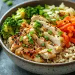 Close-up of a high protein chicken rice bowl with vegetables and herbs