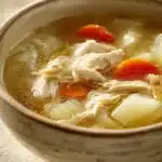 Close-up of Italian Penicillin Soup with visible ingredients in a bright setting.