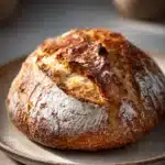 Close-up of freshly baked bread with a golden crust, highlighting texture and warmth.
