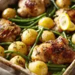 Close-up of a lemon sheet pan dinner with chicken and lemon slices on a baking tray.