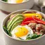 Close-up of a low carb breakfast prep with eggs and greens on a white plate