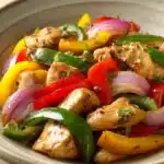 Close-up of Mexican chicken stir-fry with colorful vegetables in a bright setting.