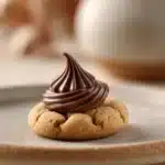 Close-up of peanut butter cookies topped with Hershey kisses on a minimal background.