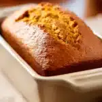 Close-up of freshly baked pumpkin bread in a bread machine with a clean background.