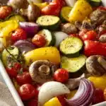 Close-up of colorful roasted vegetables on a sheet pan with a clean background.