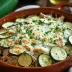 Close-up of a rotisserie chicken and zucchini casserole with golden cheese topping