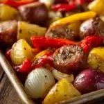Close-up of a sheet pan dinner with sausage and potatoes, featuring bright and natural lighting.
