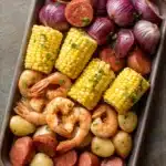Close-up of a colorful sheet pan shrimp boil with corn, potatoes, and shrimp.