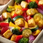 Close-up of roasted sheet pan tofu with colorful vegetables on a baking tray