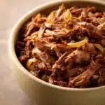 Close-up of slow cooker shredded beef with rich textures and warm lighting