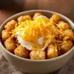 Close-up of a tater tot breakfast bowl with eggs, cheese, and herbs