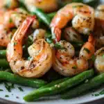 Close-up of air fryer shrimp and green beans with bright natural lighting.