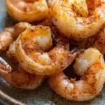 Close-up of air fryer shrimp with golden crispy texture on a clean white plate.