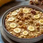 Close-up of banana bread baked oatmeal with a golden crust and minimal background.