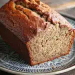 Close-up of freshly baked banana bread on a wooden board with a clean background.