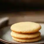 Close-up of crispy sugar cookies on a clean background with warm lighting.