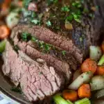 Close-up of crock pot beef loin with rich sauce and herbs.