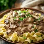 Close-up of creamy ground beef stroganoff with pasta in a white bowl.
