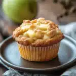 Close-up of a freshly baked granny smith apple muffin with a golden crust.