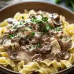 Close-up of ground beef stroganoff with creamy sauce and herbs.