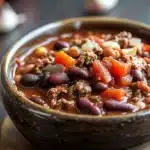 Close-up of a hearty beef chili in a crock pot with visible beans and beef chunks.