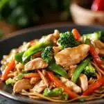 Close-up of high protein chicken lo mein with vegetables in a bright setting.