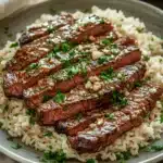 Close-up of honey butter garlic steak and rice skillet with bright, warm lighting.