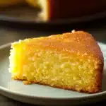 Close-up of a lemon cake with a slice cut out, showcasing its moist texture and vibrant yellow color.