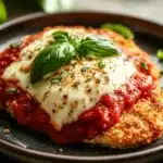 Close-up of low calorie chicken parm with creamy sauce and herbs