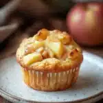 Close-up of a muffin with apple pie filling, showcasing a golden crust and warm, inviting texture.