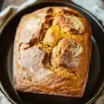 Close-up of freshly baked pumpkin bread in a dutch oven with a golden crust