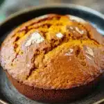 Close-up of freshly baked pumpkin bread in a Dutch oven with a golden crust.