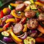 Close-up of roasted sheet pan vegetables and sausage with bright colors and textures