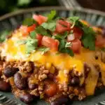 Close-up of a cheesy slow cooker chili cheese casserole with melted cheese and herbs