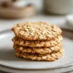 Close-up of thin and crispy oatmeal cookies on a white plate with a clean background.