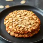 Close-up of thin and crispy oatmeal cookies on a white plate with a clean background.