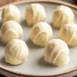 Close-up of a vanilla cake truffle with a smooth, creamy texture on a minimal background.